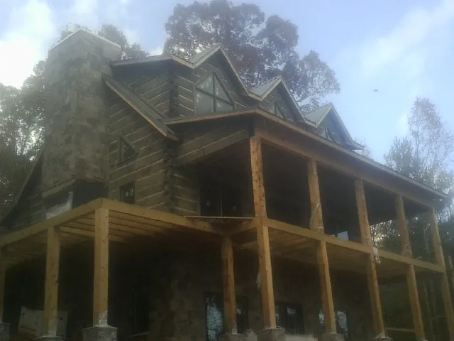 Stone chimney and dormers on a large log home with a timber porch in Hagerstown
