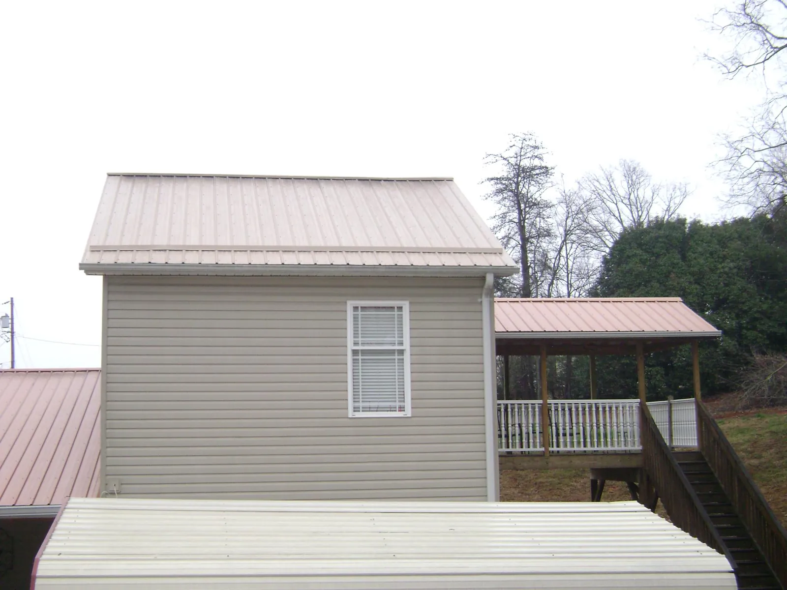 Tan metal roofs on a two story addition and attached porch, from a Roof Replacement job in Hagerstown